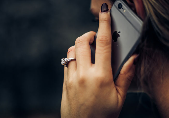 Close-up of a woman holding a phone during an emotional conversation about losing a friend to a tumour.