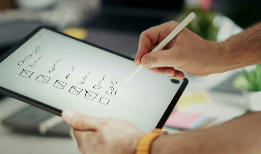 Person using a digital tablet and stylus to check off items on a checklist illustrating practical psychology tricks in action