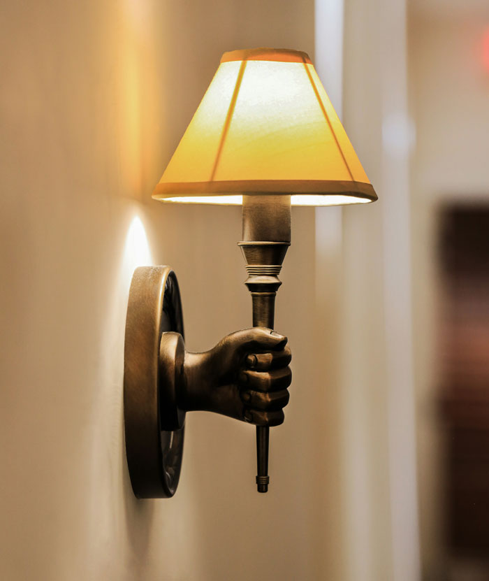 Wall sconce shaped like a hand holding a torch-style lamp, symbolizing harmless secrets in relationships decor concept.