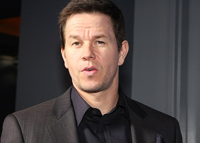 Actor Mark Wahlberg wearing a dark suit and black shirt, captured at an event discussing celebrities who turned out to be raging jerks.