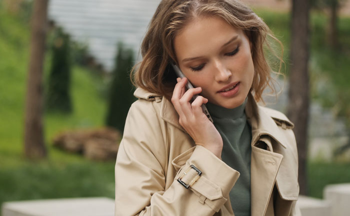 Mulher falando ao telefone ao ar livre, parecendo preocupada enquanto discutia os problemas de comportamento de seu 8º filho adotivo. Mulher falando ao telefone ao ar livre, parecendo preocupada enquanto discutia os problemas de comportamento de seu 8º filho adotivo.