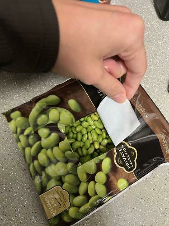 Hand opening a bag of green edamame beans, illustrating seemingly harmless things partners do that drive others insane.