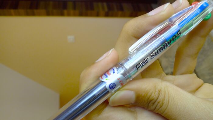 Hand holding a gel pen with multiple colored ink options, a childhood item many thought was unique.