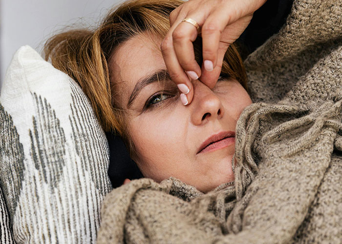 Worried woman lying in bed with hand on forehead, tired and concerned about man caring for his baby at 4 AM.