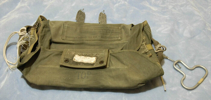 Vintage military-style green parachute pack laid flat on a gray surface related to DB Cooper investigation by FBI Vintage military-style green parachute pack laid flat on a gray surface related to DB Cooper investigation by FBI