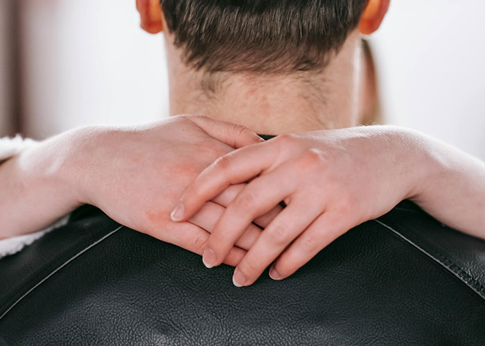Close-up of a couple hugging, showing intertwined hands and a leather jacket, symbolizing a messy love triangle.