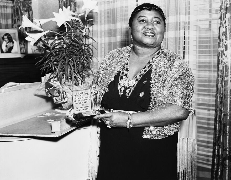 Hattie McDaniel segurando um Oscar por conquista notável, relacionado à primeira pessoa negra a ganhar um Oscar.