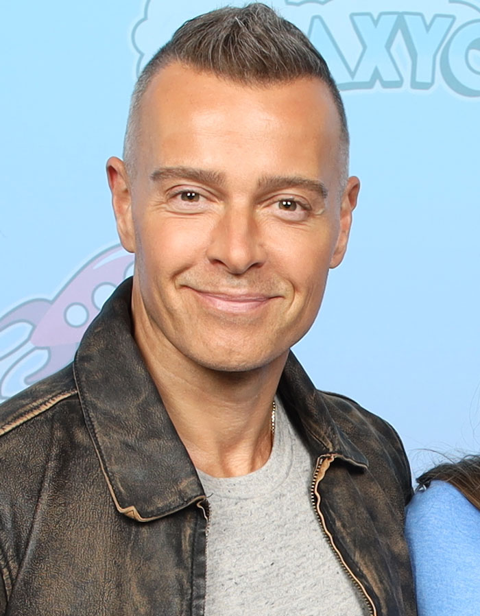 Man smiling wearing a leather jacket and gray shirt, representing people exposing shocking corporate secrets to customers