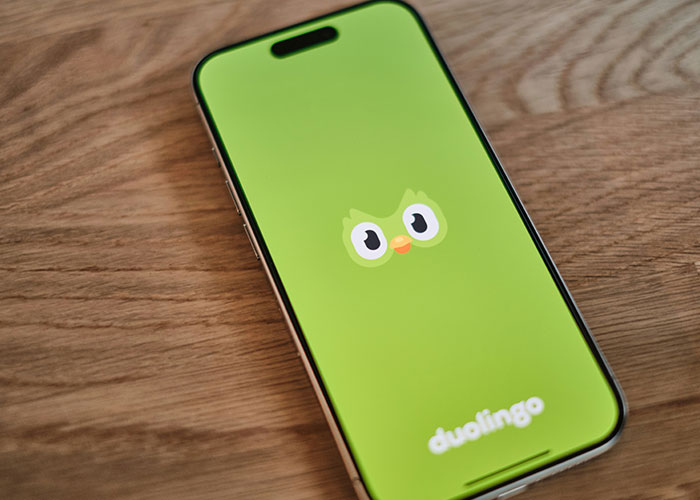 Smartphone displaying Duolingo app icon on wooden surface, illustrating language learning and personal growth after divorce.
