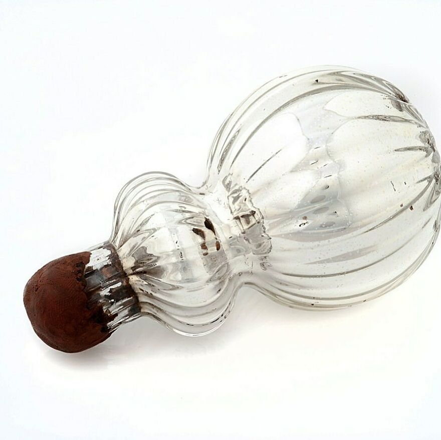 Clear vintage glass bottle with a decorative stopper, one of the curious objects with dazzling origins.