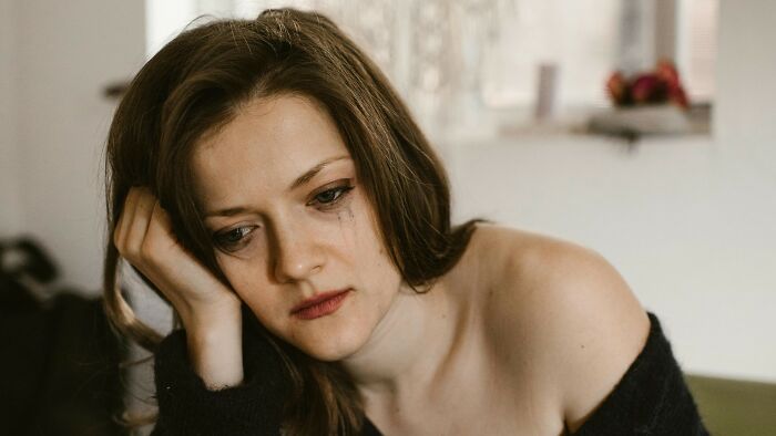 Young woman with tear-streaked face feeling distressed, reflecting on peer pressure.