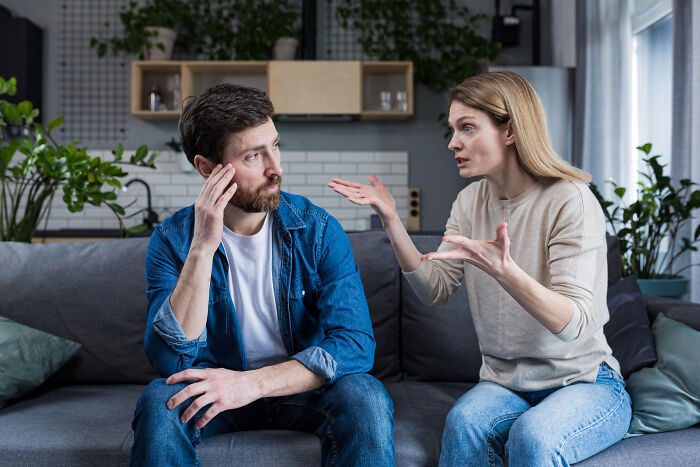Couple having an intense argument on couch, illustrating tough reasons people stay in a relationship despite hating their partner.