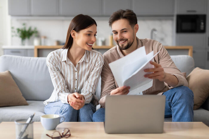 Young woman and man reviewing documents together on laptop, discussing things women thought were part of being woman.