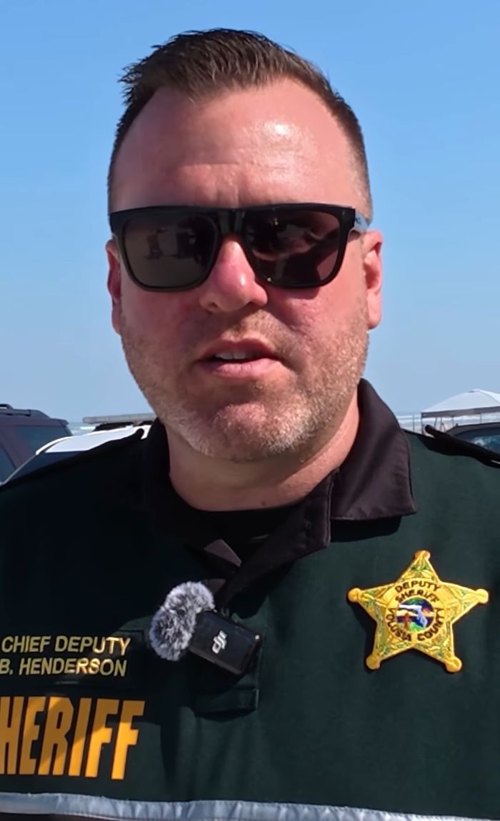 Chief Deputy in sheriff uniform speaking outdoors at Daytona Beach during spring break amid crime investigation.