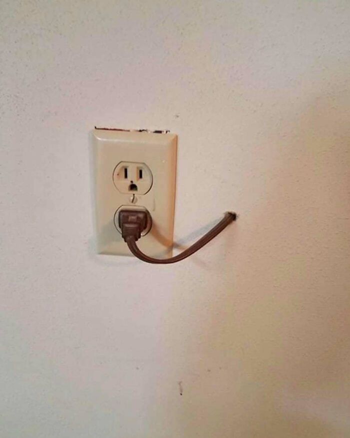 Electrical outlet with a short, cut power cord plugged in, showcasing one of the worst home design disasters.