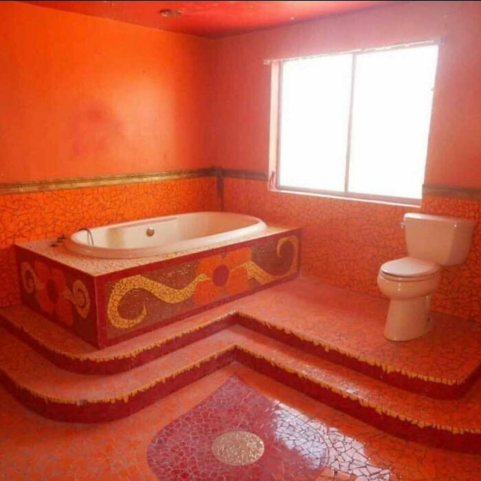 Bathroom with orange mosaic tiles and an unusual raised bathtub and toilet, showcasing home design disasters.