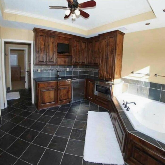 Kitchen cabinets and bathtub combination in an unusual layout showcasing home design disasters and poor aesthetics.