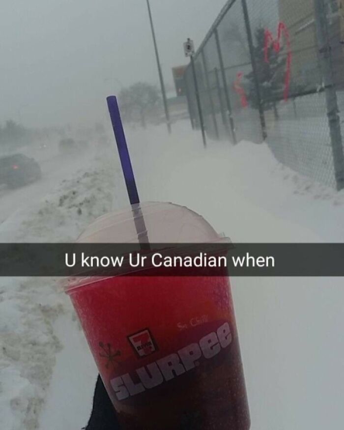 Hand holding a 7-Eleven Slurpee cup in snowy weather, illustrating funny Canada memes about Canadian habits.