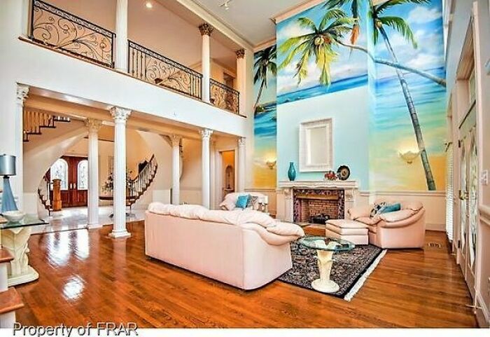 Living room with a tropical mural wall and large columns showing a striking home design disaster with mismatched styles.