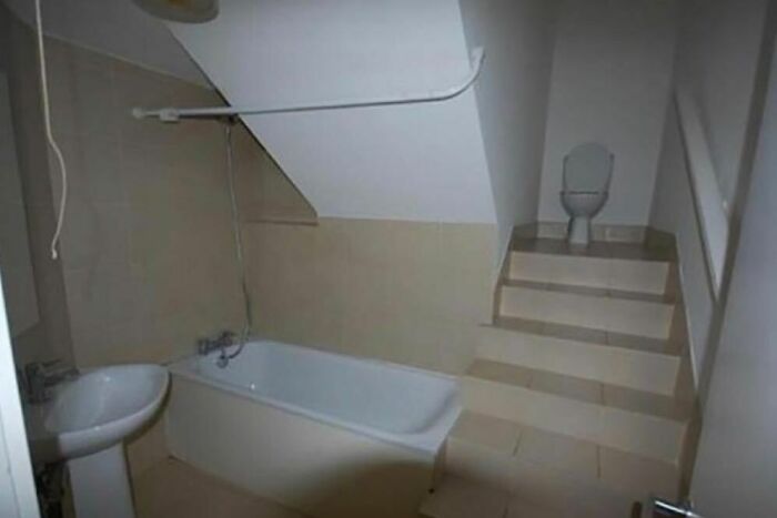 Bathroom with bathtub and sink, featuring home design disasters with awkward steps leading up to a toilet.
