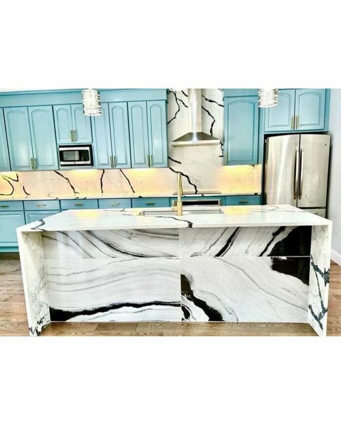 Modern kitchen with blue cabinets and a marble island featuring bold black and white design home design disasters.