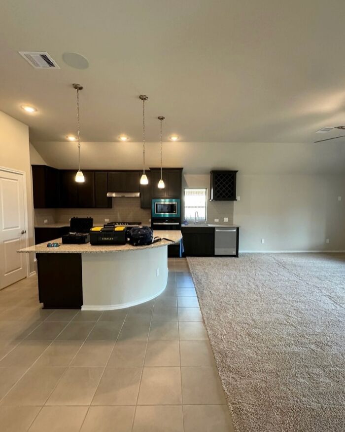 Open kitchen with tile and carpet flooring transition creating a confusing home design disaster in an otherwise modern space.