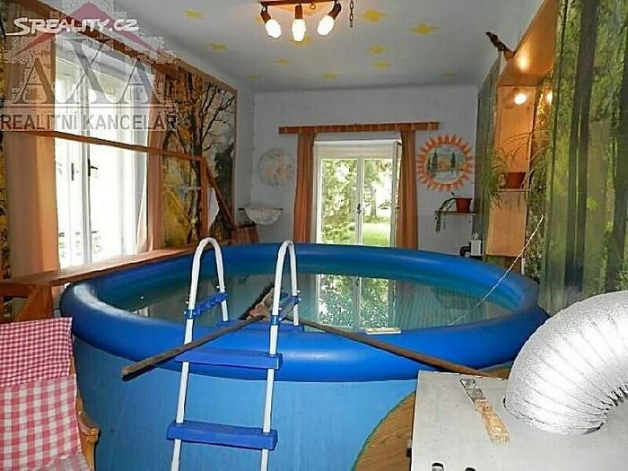 Indoor inflatable pool setup with ladder and wooden beam, illustrating home design disasters and poor aesthetic choices.