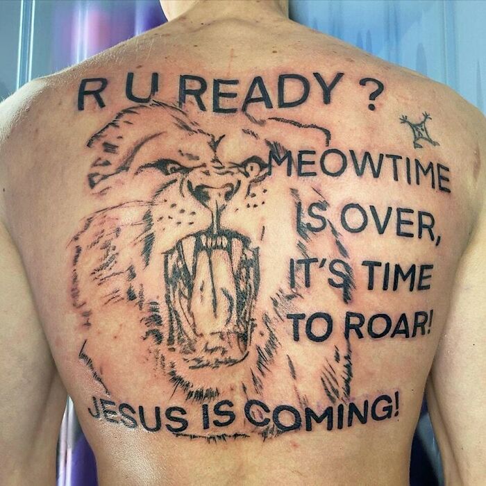 Tattoo fail of a roaring lion with misaligned text reading R U READY and other phrases on a person's back, an ink fail example.
