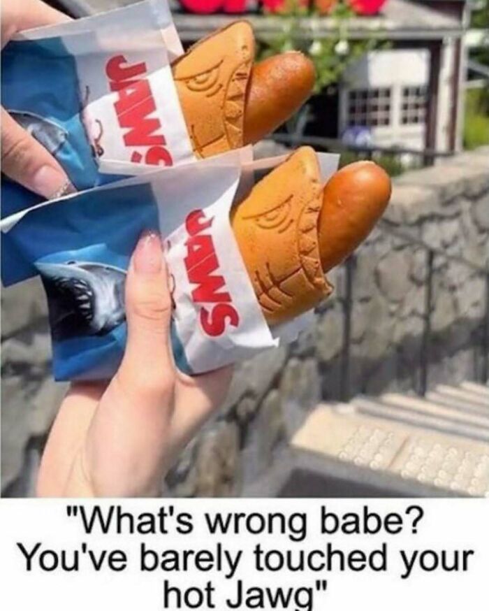 Two hands holding hot dogs in shark-themed buns with meme text about loving food and eating more than normal.