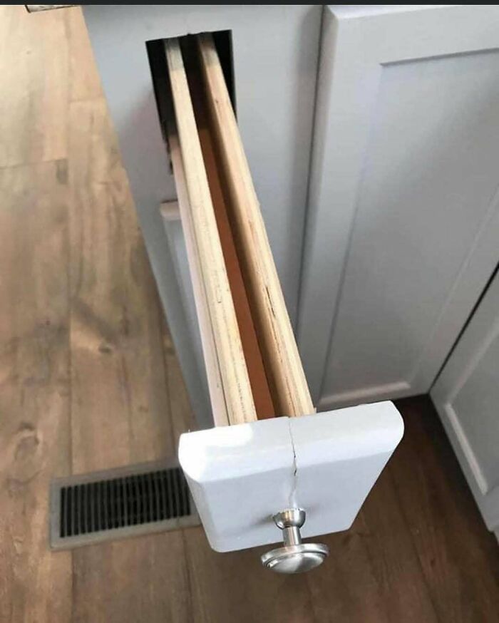 Half-built white kitchen drawer with a cracked front panel and exposed wooden interior, a home design disaster.