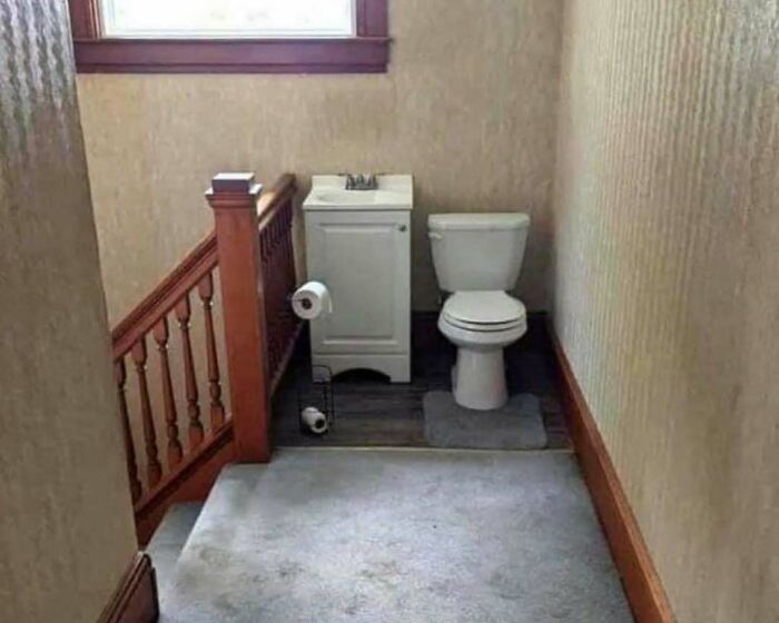 Bathroom setup with toilet and sink placed at the top of stairs, illustrating a home design disaster and poor aesthetics.