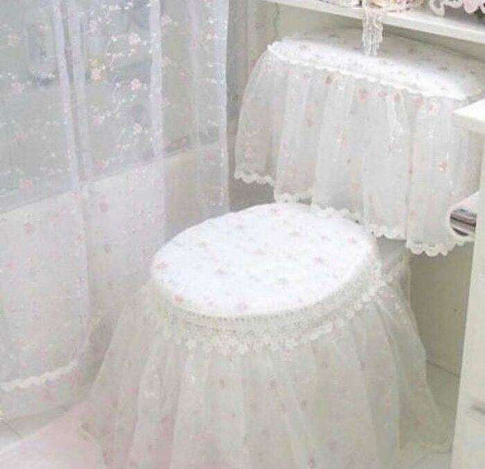 Toilet and tank covered entirely in frilly white fabric with lace, showcasing home design disasters that are impractical and unaesthetic.