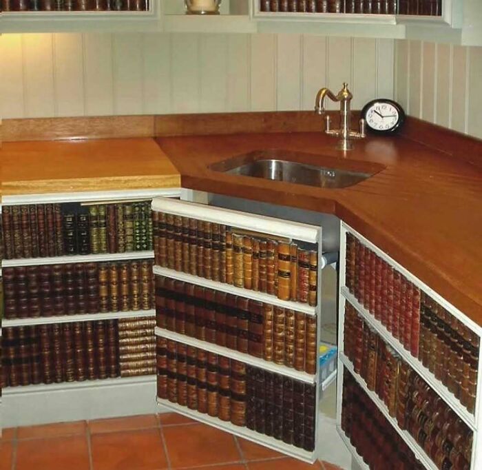 Hidden cabinet designed to look like a bookshelf in a kitchen with wooden countertop and sink, showcasing home design disasters.