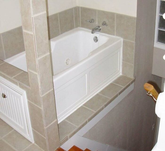 Bathtub installed next to an open stairwell, a glaring home design disaster with poor safety and aesthetic appeal.