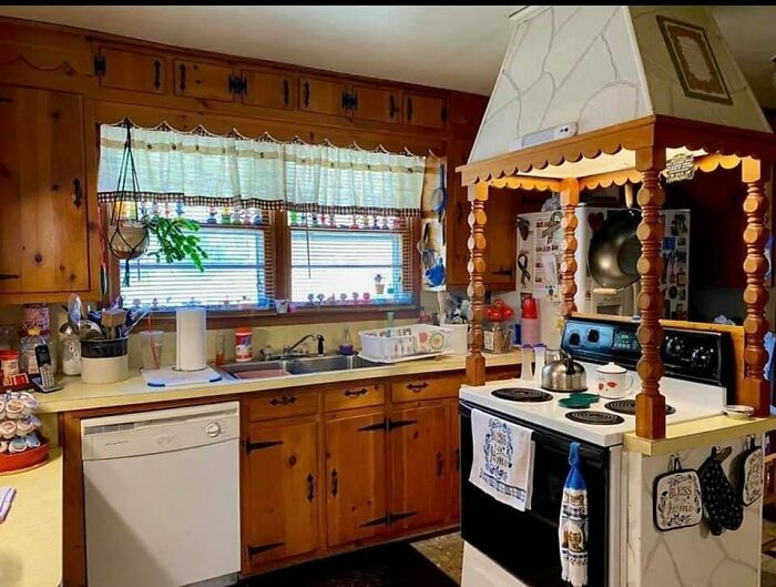 Vintage wooden kitchen with mismatched appliances and overcomplicated stove hood design, showing home design disasters.