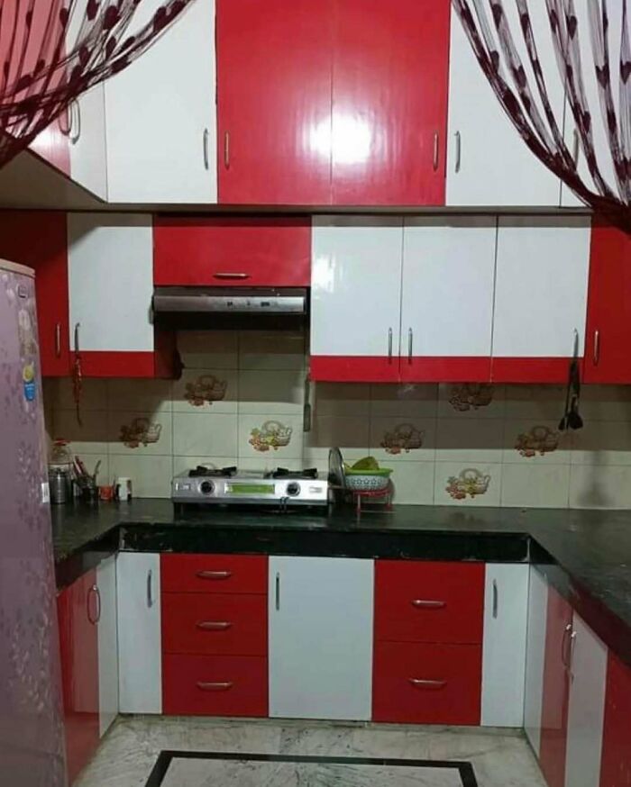 Small kitchen with inconsistent cabinet design and mismatched red and white colors, a home design disaster example.