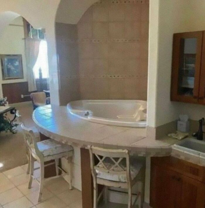 Bathroom with bathtub surrounded by counter space and chairs, showcasing unusual home design disasters and poor aesthetics.