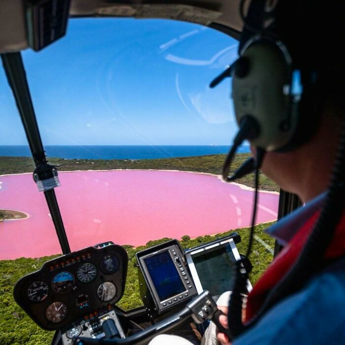 Pilot flying over a vibrant pink lake, showcasing unreal photos that prove reality is incredible and far from boring.