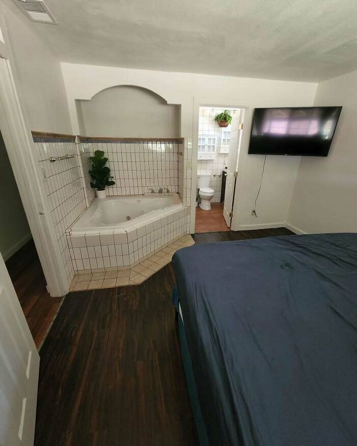 Bedroom with a jacuzzi tub awkwardly placed next to the bed and a wall-mounted TV highlighting home design disasters.