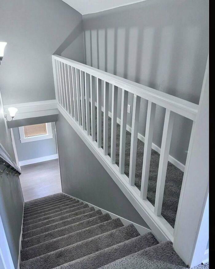 Narrow staircase with a railing mounted in the middle, creating a confusing and impractical home design disaster.