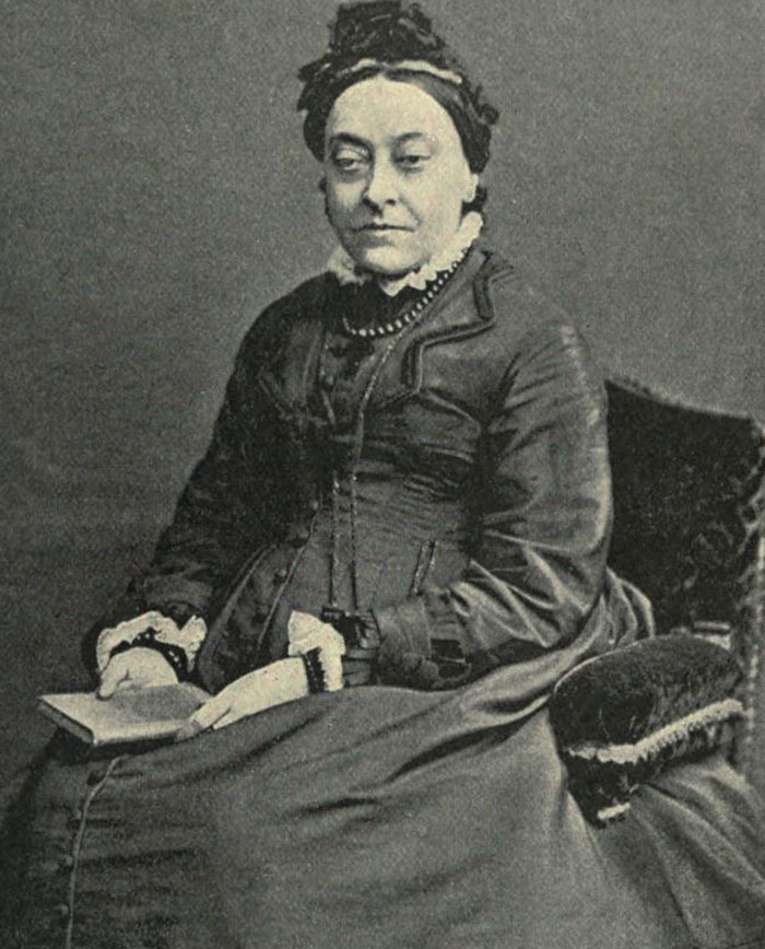 Black and white portrait of a seated historical woman reading a book related to notable figures who likely passed away as virgins.