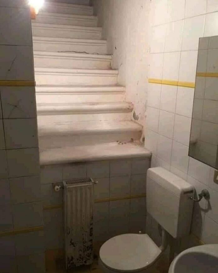 Bathroom with stairs leading directly into the space, showcasing a home design disaster with poor layout and aesthetics.