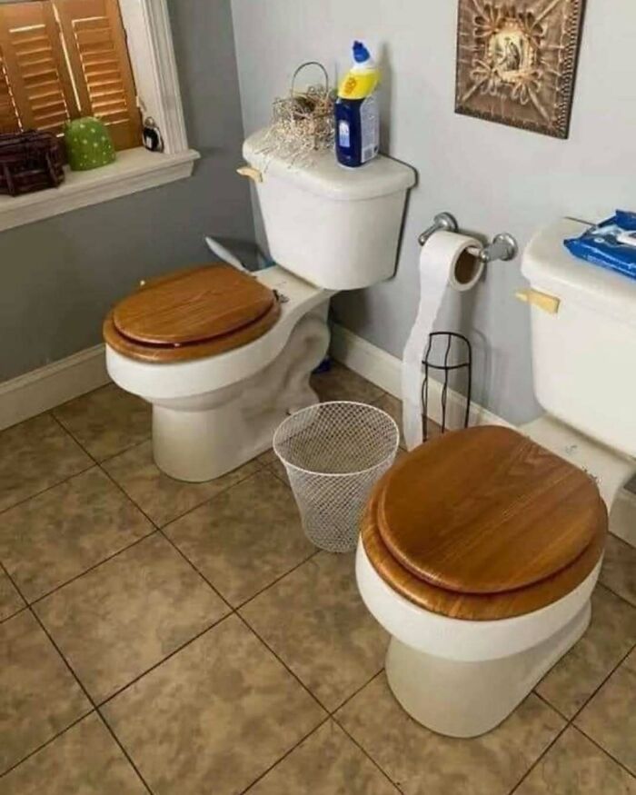 Two toilets with wooden seats placed side by side in a bathroom, illustrating home design disasters and poor layout choices.