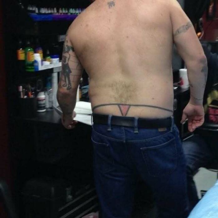 Man with a tattoo fail of a belt design on his lower back, showcasing ink mistakes that led to permanent regrets.