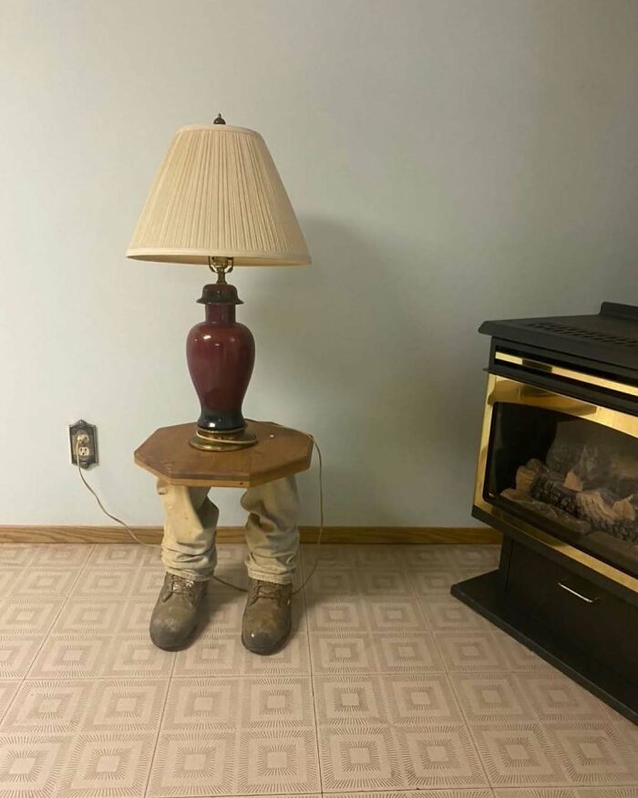 Table with pants and boots acting as legs holding a lamp, an unusual home design disaster with zero aesthetic sense.