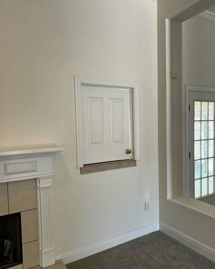 Small door installed high on wall above tiled ledge, an unusual and confusing home design disaster in a modern living room.