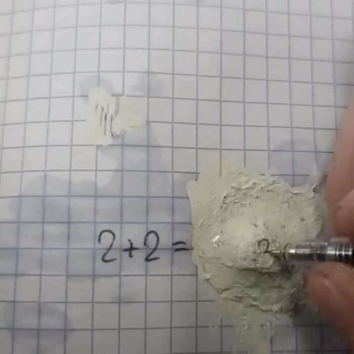 Close-up of hand correcting a math equation on grid paper, capturing a moment of confusion in existential crisis memes.