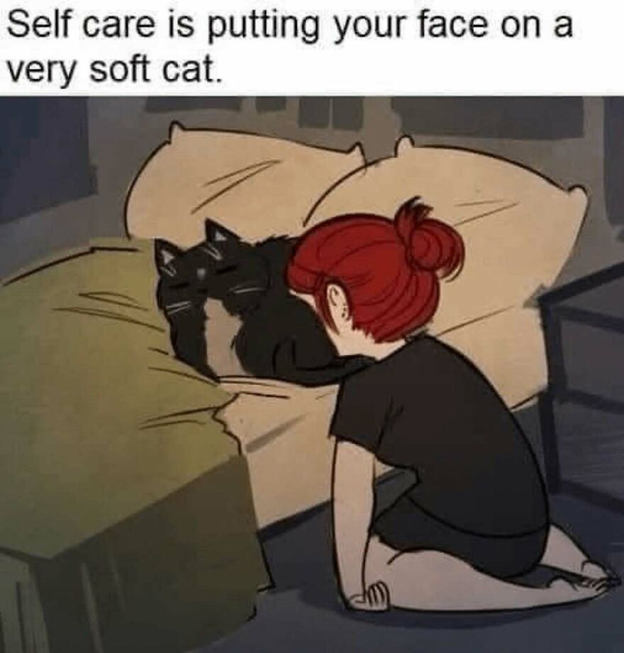 Woman with red hair kneeling by bed, resting her face on a very soft black cat, showcasing cat memes and self care.