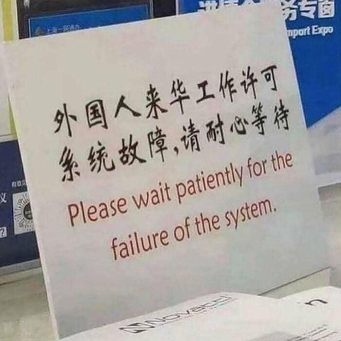 Sign with bilingual text humorously asking to wait patiently for the failure of the system, reflecting memes about existential crisis.