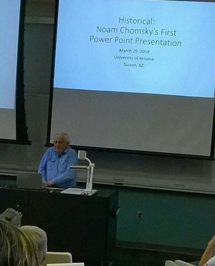 Elderly man giving a presentation in a lecture hall with a slide, memes that might cure or worsen existential crisis.